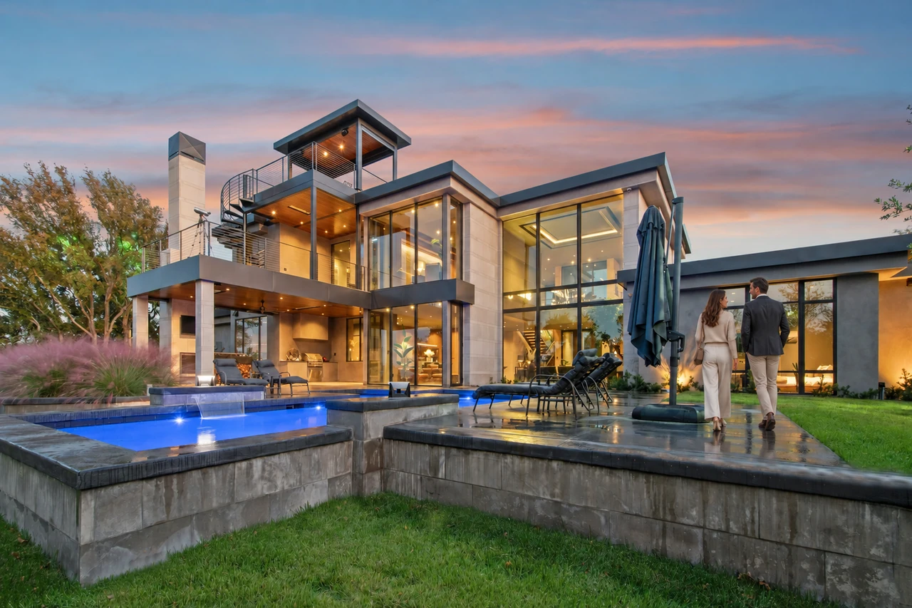 An elegantly dressed couple approaching a contemporary residence beside its pool at dusk